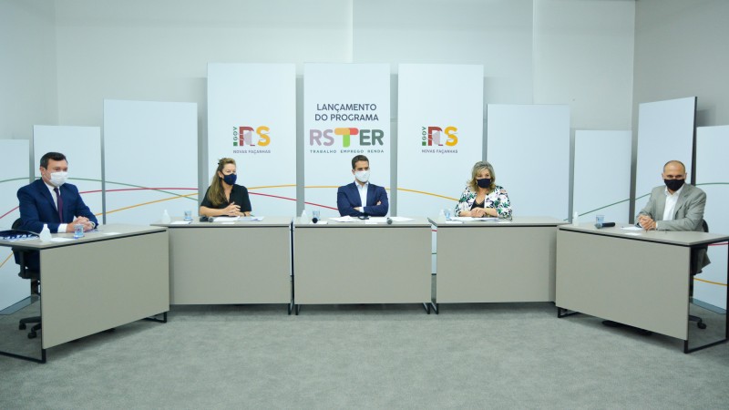 Imagem da sala com os convidados sentados a mesa.