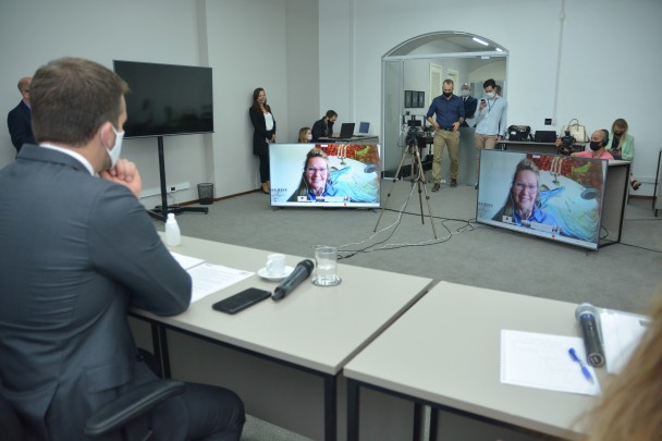 Imagem dos participantes do evento assistindo a secretária Regina Becker em seu momento de fala. 