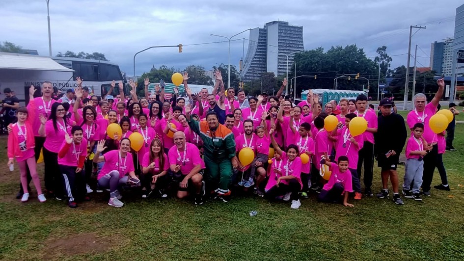 foto colorida dos participantes da corrida todos de camiseta rosa e calças pretas