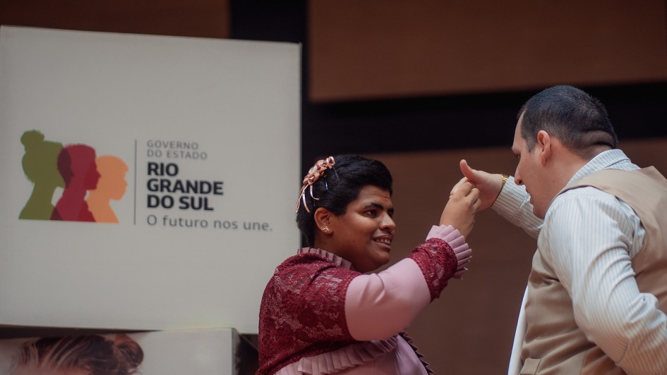 casal dança com a logomarca do governo do estado no fundo